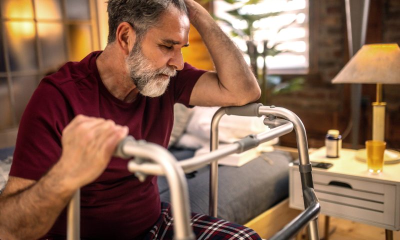 Thoughtful elderly man sitting alone at home with his walking cane Thoughtful elderly man sitting alone at home with his walking cane